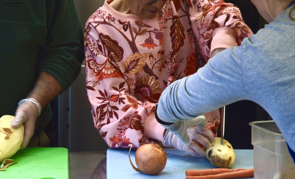 Participant cutting a potato on a blue cutting board