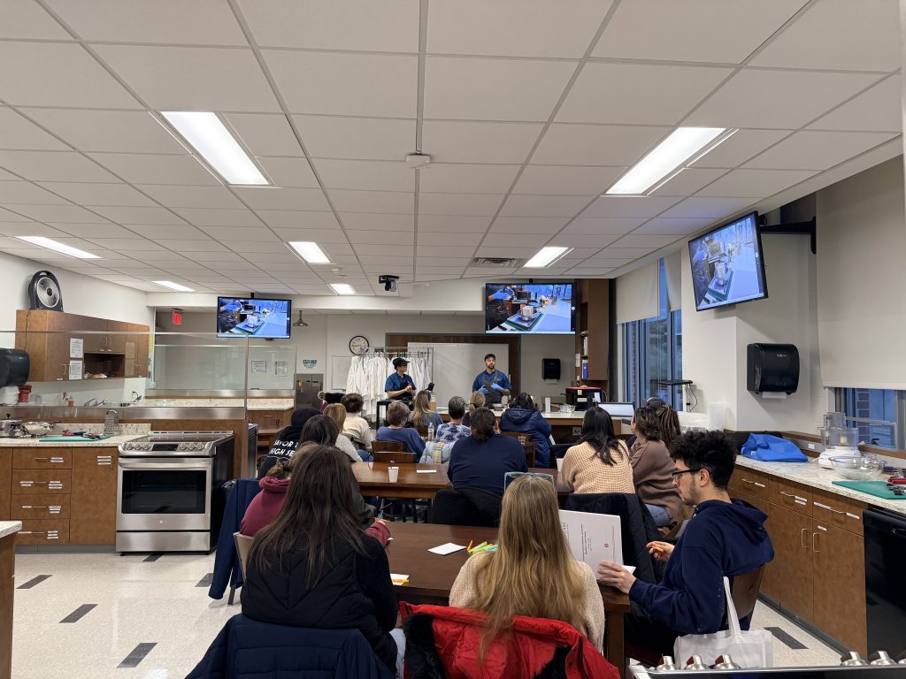 Participants gathered to observe chef food demos at the front of the room