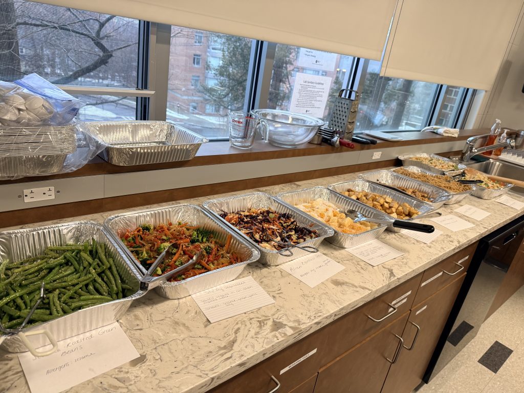 Array of cooked foods which are labeled and separated in aluminum pans