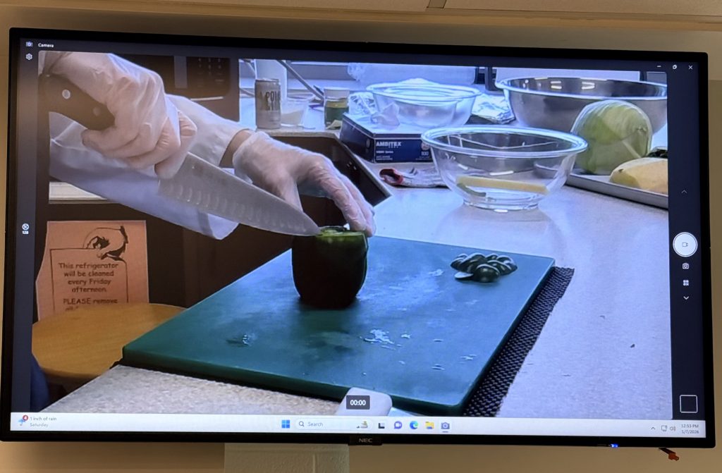 Food demo showing how to cut a green pepper shown on the TV screen
