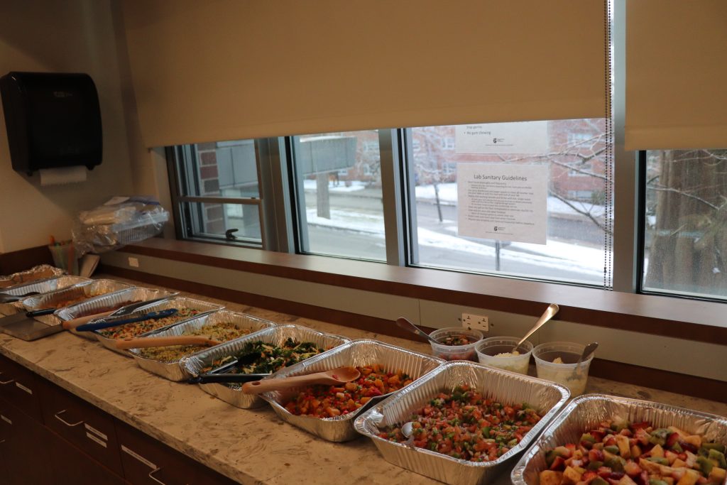 Array of cooked foods which are labeled and separated in aluminum pans