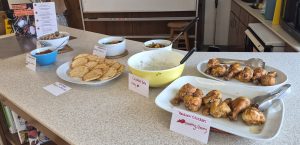 An Array of food, some in bowls and some on plates with lists of allergens on notecards.