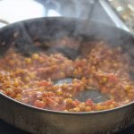Simmering red chickpea paste in a skillet