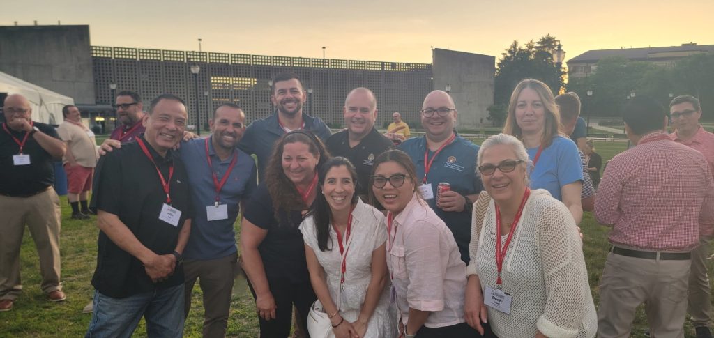 JSI chefs, staff, and CECAP nutrition staff posing for a photo outside in a field with a brick building in the background under sky.