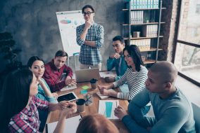 Company of nice stylish attractive beautiful handsome specialists wearing casual sitting talking new financial growth career promotion at industrial interior workplace workstation