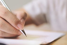 Hand of man signing signature filling in application form document